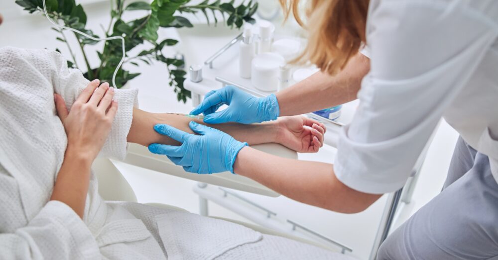 Provider in gloves administering an IV therapy drip