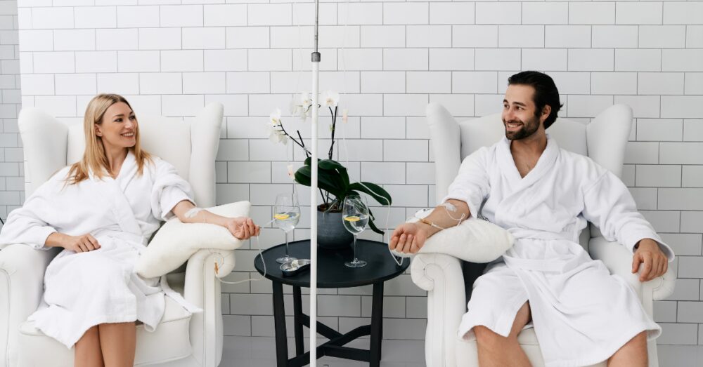 Man and woman in spa robes relaxing side by side during an IV therapy session