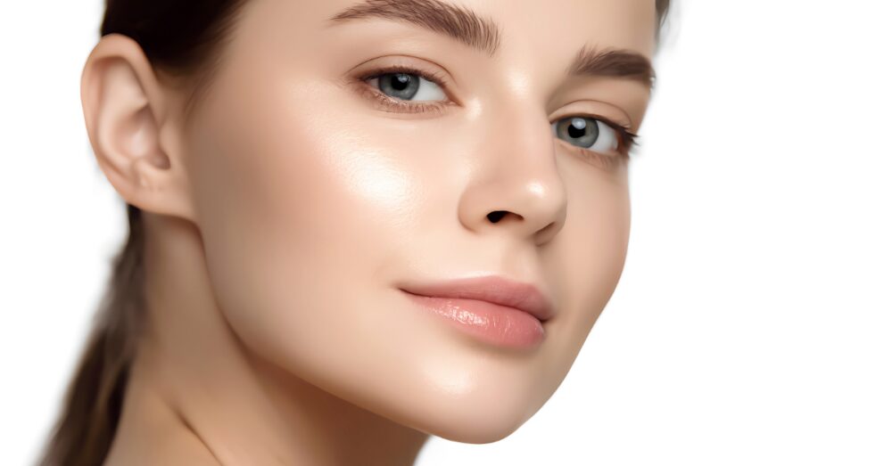Close-up of a woman with smooth, clear skin looking over her shoulder against a light background