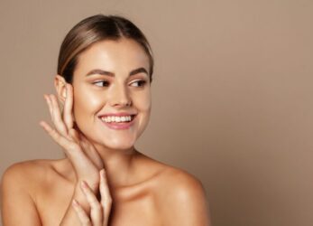 Woman touching her cheek while looking to the side, smiling
